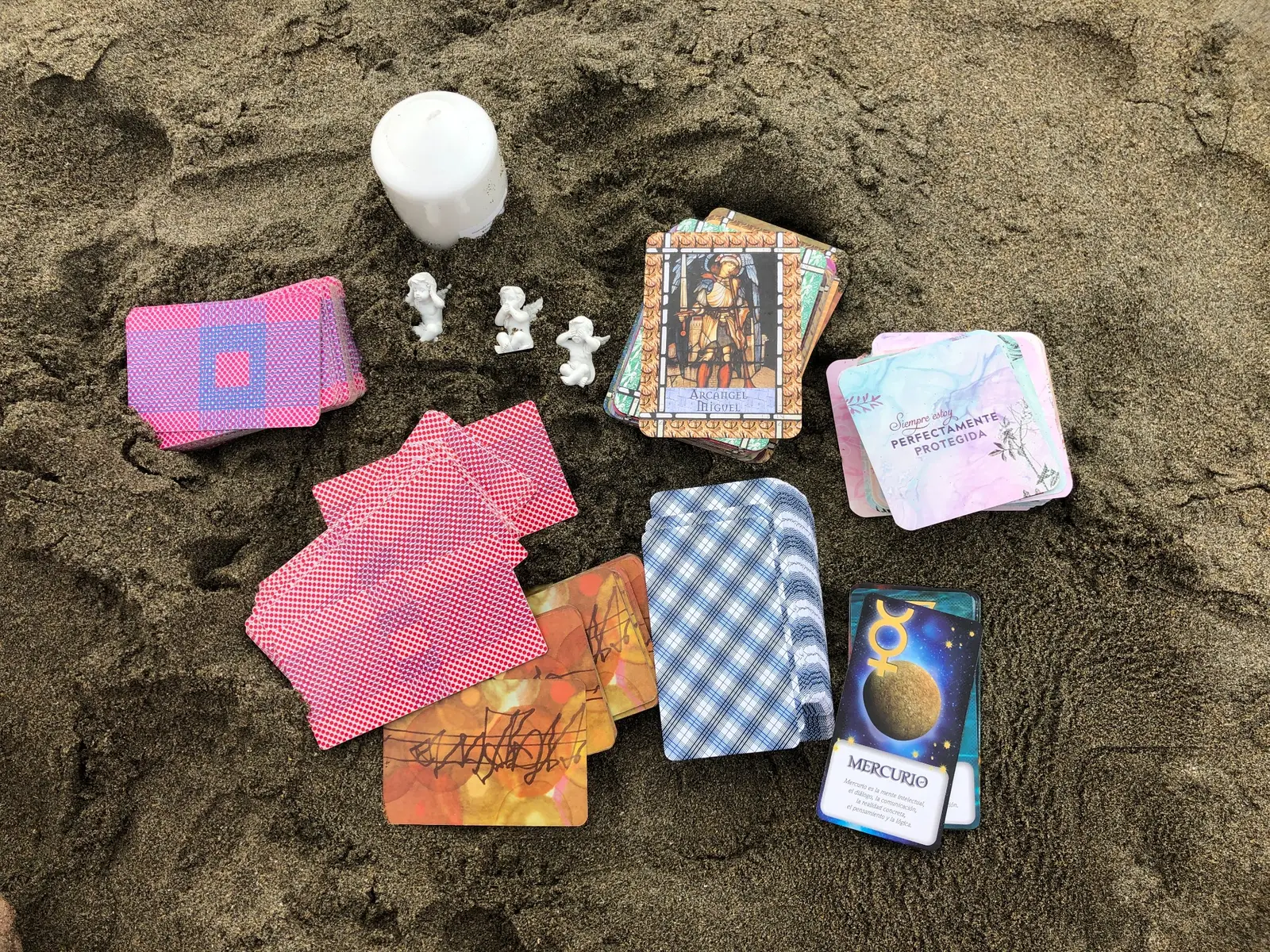 Cartas y oráculos de Tarot Amanecer dispuestos sobre la arena